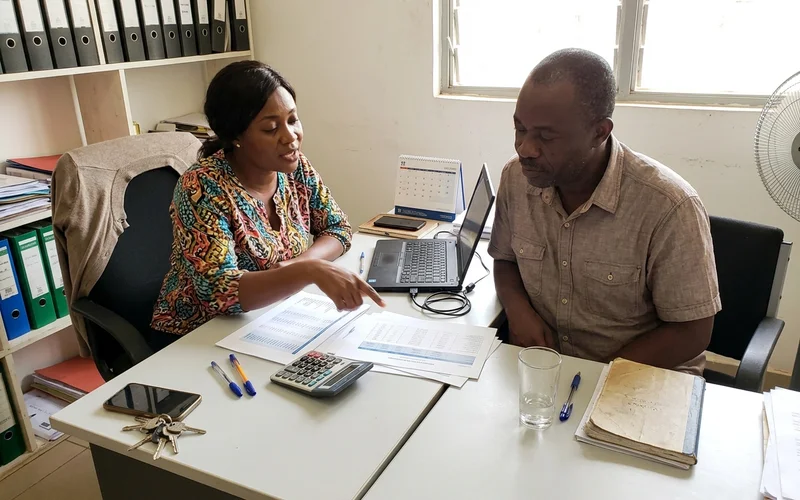 Account manager explaining monthly ad figures to a client across a desk