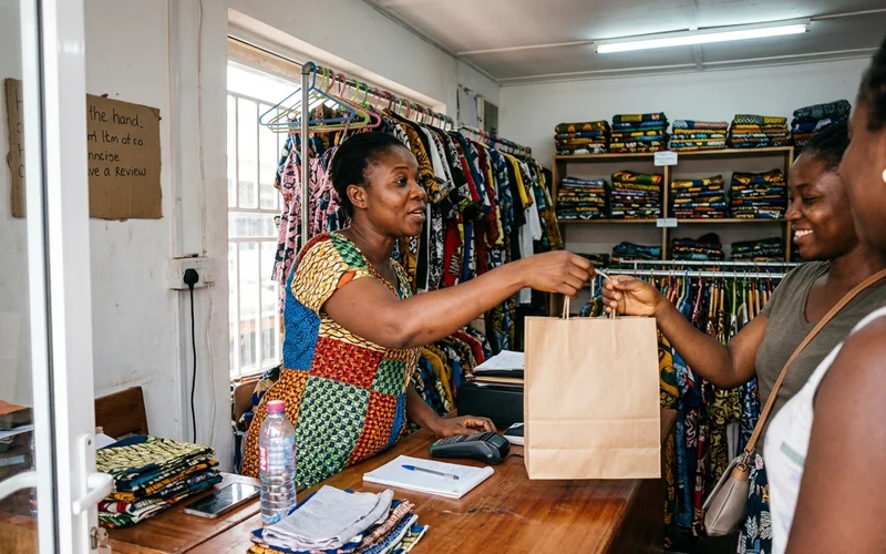 Boutique owner asking a customer for a Google review while handing over a bag
