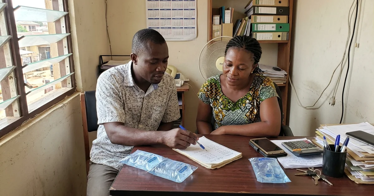 Two business partners discussing a marketing budget on a notepad at a small office table