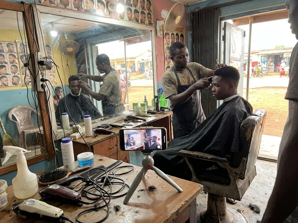 Filming a short TikTok video in a Kumasi barbershop